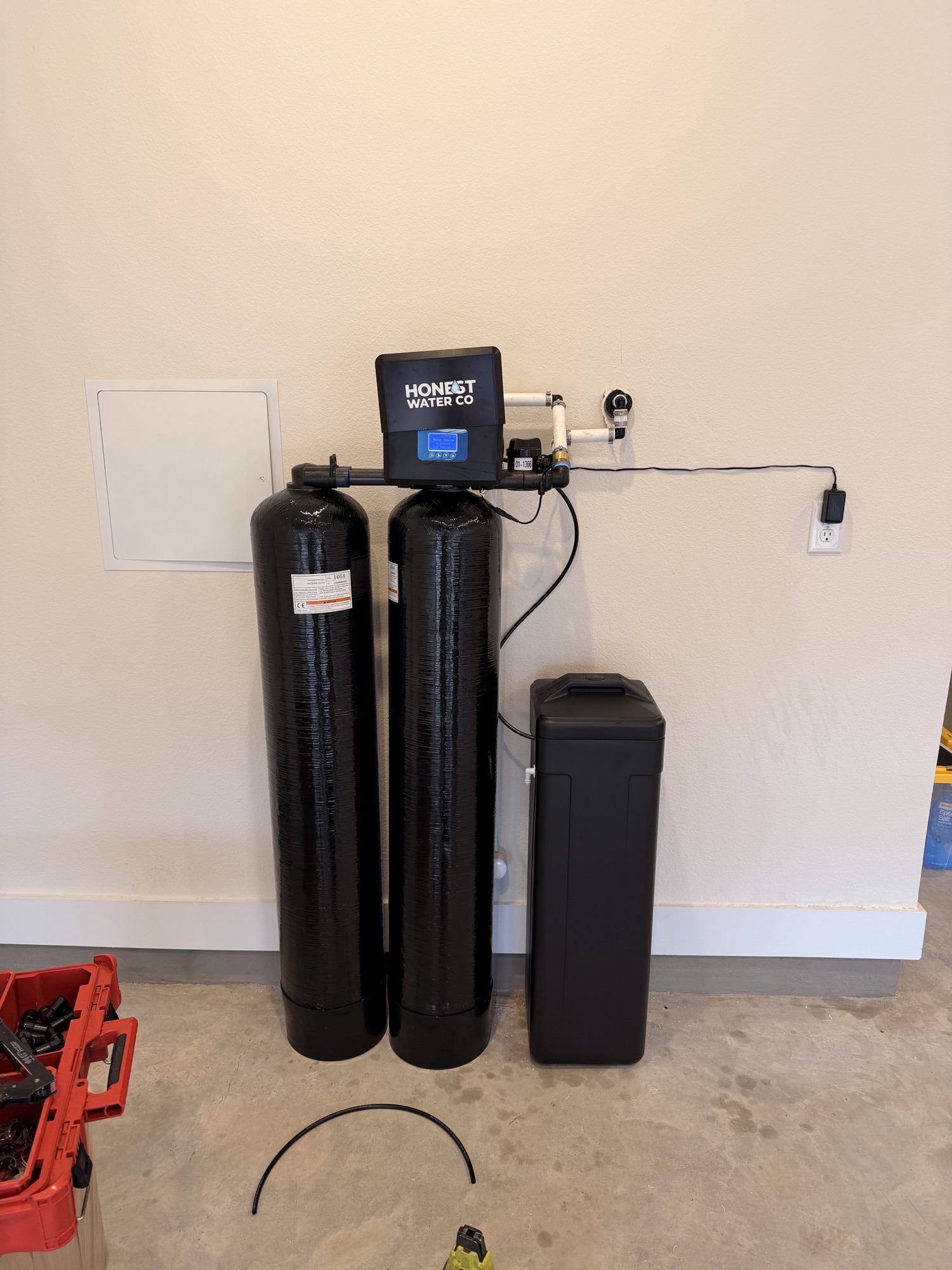Twin treatment tanks installed beside a garage wall